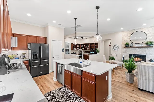 a kitchen with stainless steel appliances granite countertop a stove top oven a sink dishwasher and a fireplace with wooden floor