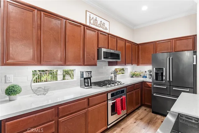 a kitchen with stainless steel appliances granite countertop a refrigerator a sink dishwasher stove and oven with wooden cabinets