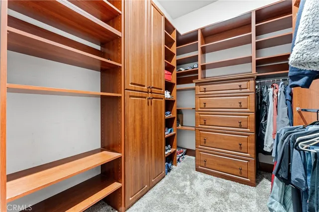 a view of walk in closet with clothes and shoes