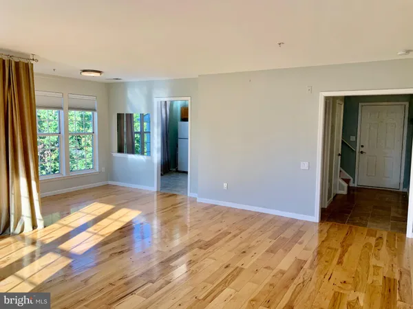 a view of an empty room with window and wooden floor