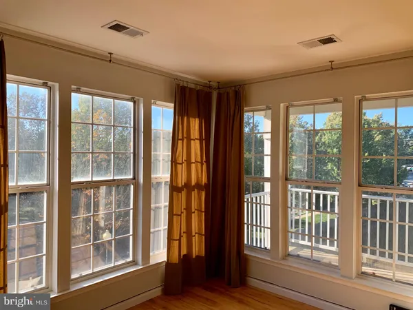 a view of an empty room with wooden floor and windows