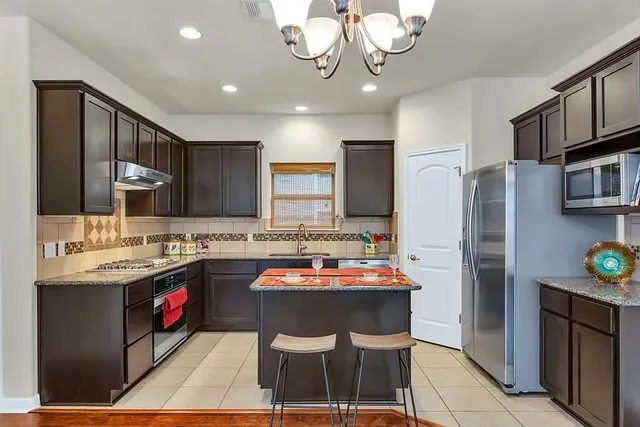 a kitchen with stainless steel appliances granite countertop a sink refrigerator and cabinets
