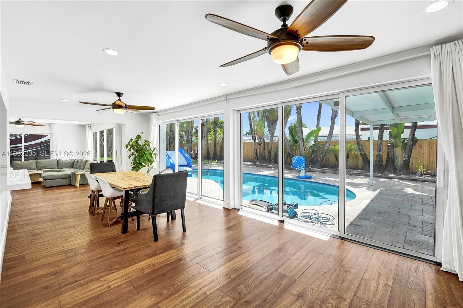 3350 North 40th Street Hollywood, FL 33021 - Photo 81 of 100 a dining room with wooden floor a chandelier fan a glass table and chairs
