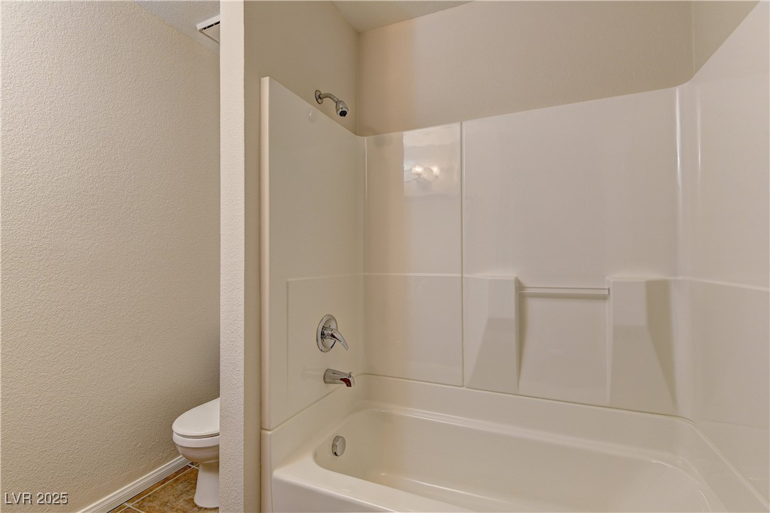 3145 East Flamingo Road, Unit 2080 Las Vegas, NV 89121 - Photo 19 of 26 Bathroom featuring toilet, tub / shower combination, baseboards, a textured wall, and tile patterned flooring