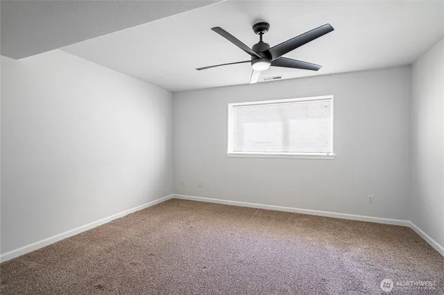 an empty room with a window and a fan