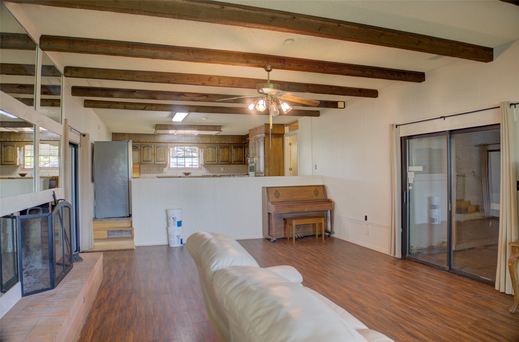 12420 South Garnett Road Broken Arrow, OK 74011 - Photo 16 of 44 Exposed ceiling beams, wood-finish flooring, built-in fireplace, ceiling fan, and sliding glass door