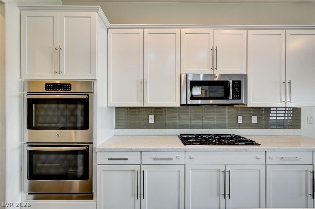 8197 Riley Love Street Las Vegas, NV 89139 - Photo 18 of 48 White cabinetry, sleek stainless steel appliances, and a gas cooktop create a contemporary culinary space.