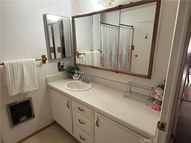 a bathroom with a sink and a mirror white cabinets