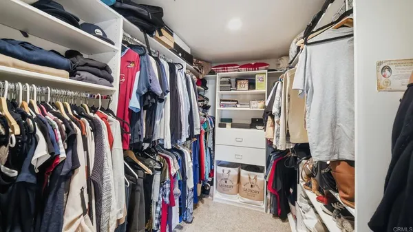 a view of walk in closet with clothes and shoes