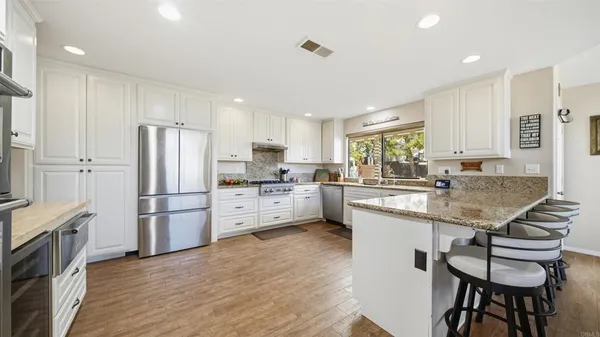 a kitchen with stainless steel appliances granite countertop a stove refrigerator sink and microwave