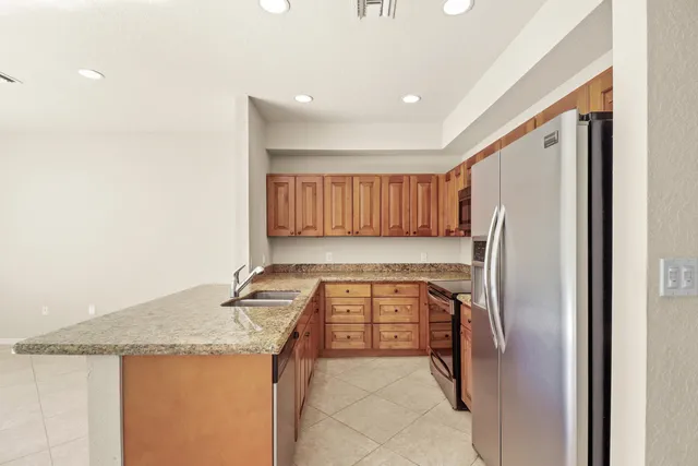 a kitchen with granite countertop a refrigerator and a stove top oven