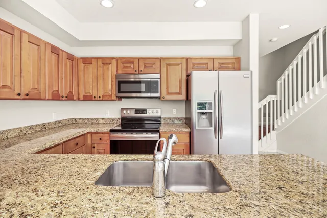 a kitchen with granite countertop a refrigerator sink and stove