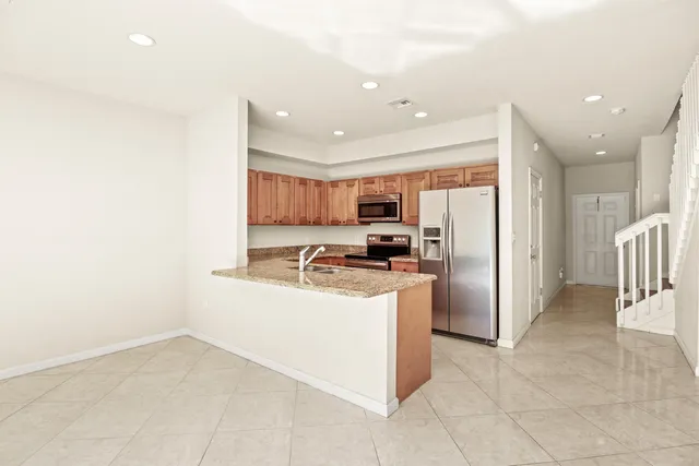 a kitchen with stainless steel appliances granite countertop a refrigerator and a stove top oven