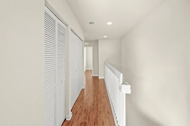 a view of a hallway with wooden floor and staircase