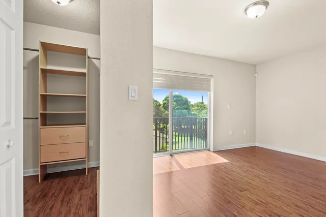 a view of an empty room with a window and wooden floor
