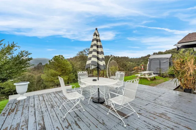 a view of a roof deck with table and chairs a barbeque with wooden floor and fence