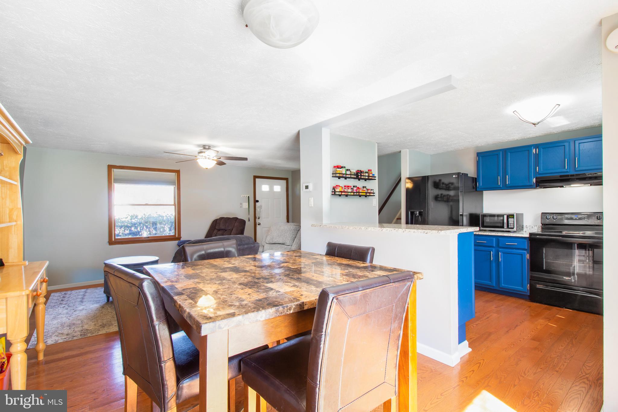 7009 Deepage Drive Columbia, MD 21045 - Photo 6 of 34 a kitchen with stainless steel appliances granite countertop a stove a refrigerator a kitchen island a dining table and chairs with wooden floor