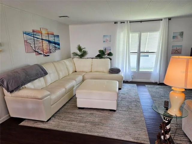a living room with furniture floor to ceiling window and wooden floor
