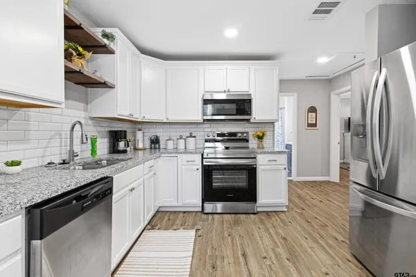 a kitchen with stainless steel appliances granite countertop a refrigerator sink and stove