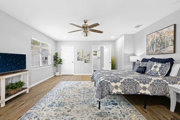 a bedroom with a bed a dresser and paintings on the wall
