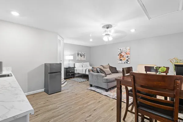 a living room with furniture and a dining table with wooden floor