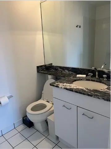 a bathroom with a granite countertop toilet and a sink