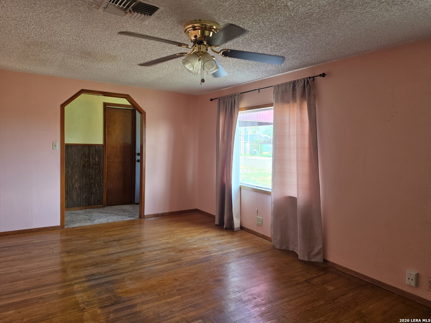 508 Nueces Cotulla, TX 78014 - Photo 6 of 14 an empty room with wooden floor chandelier fan and windows