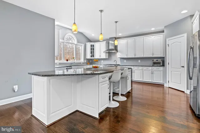 a kitchen with kitchen island granite countertop a sink cabinets and wooden floor