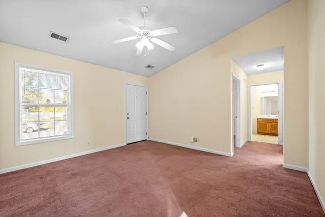 an empty room with chandelier fan and windows