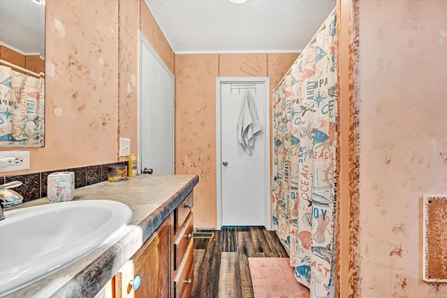 a bedroom with a bed and dresser with wooden floor