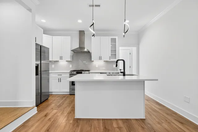 a kitchen with stainless steel appliances a sink stove and wooden floor