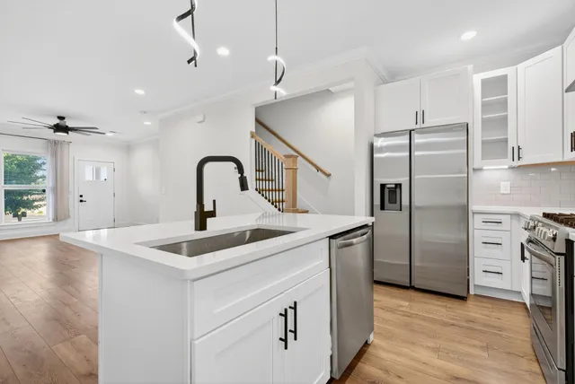 a kitchen with stainless steel appliances kitchen island a refrigerator sink and cabinets