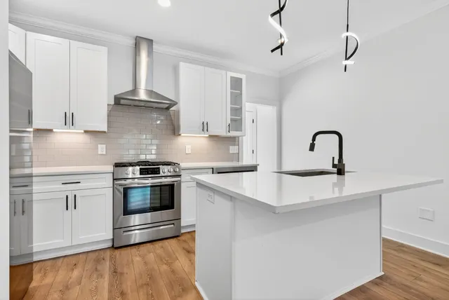 a kitchen with kitchen island stainless steel appliances a sink stove and refrigerator