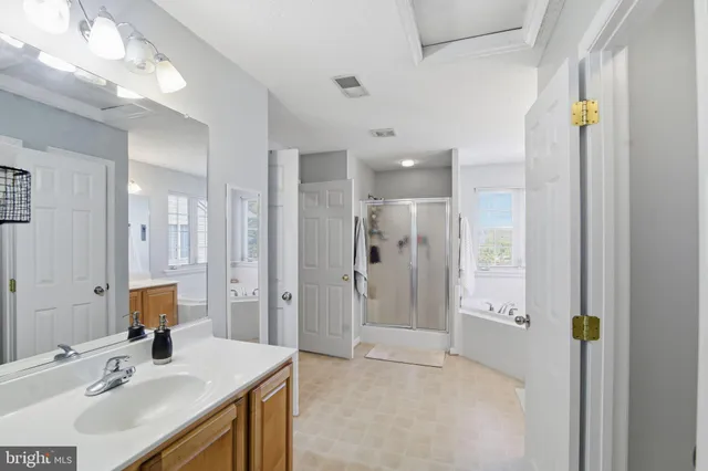 a bathroom with a sink vanity granite tub shower and a mirror