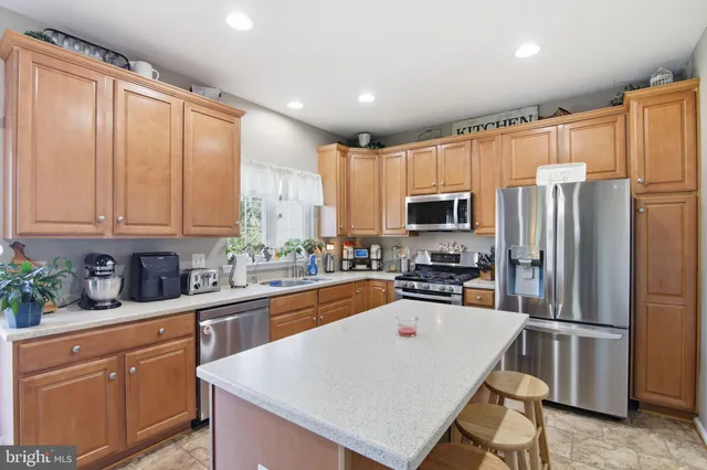 a kitchen with stainless steel appliances granite countertop a refrigerator a stove top oven a sink dishwasher and white cabinets with wooden floor