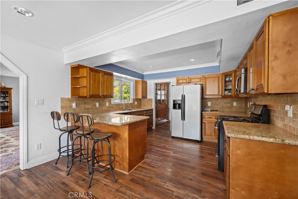 24405 Derian Drive Newhall, CA 91321 - Photo 11 of 36 a kitchen with stainless steel appliances granite countertop a table chairs refrigerator and wooden cabinets