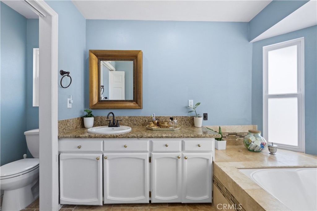 24405 Derian Drive Newhall, CA 91321 - Photo 26 of 36 a bathroom with a granite countertop sink a toilet and mirror