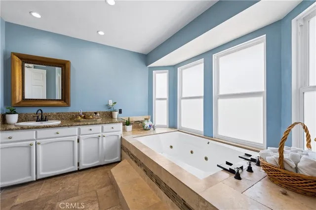 a bathroom with a granite countertop tub sink and mirror