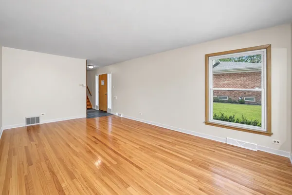 a view of an empty room with wooden floor and a window