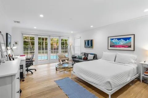 a spacious bedroom with a bed a large window and wooden floor