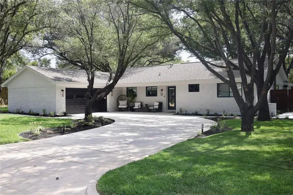 a front view of a house with a garden and trees
