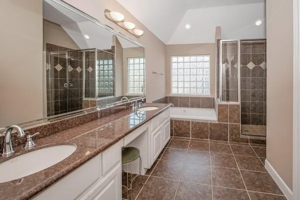 a spacious bathroom with a granite countertop sink a mirror and a bathtub