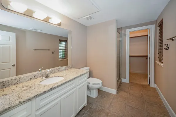 a bathroom with a granite countertop sink a toilet and a mirror