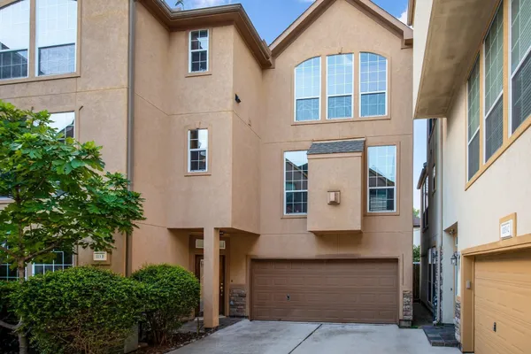 front view of a brick house with a yard and potted plants