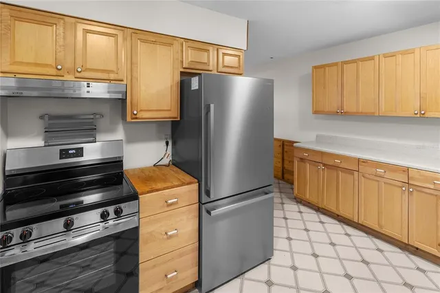 a kitchen with stainless steel appliances granite countertop a refrigerator and a stove top oven