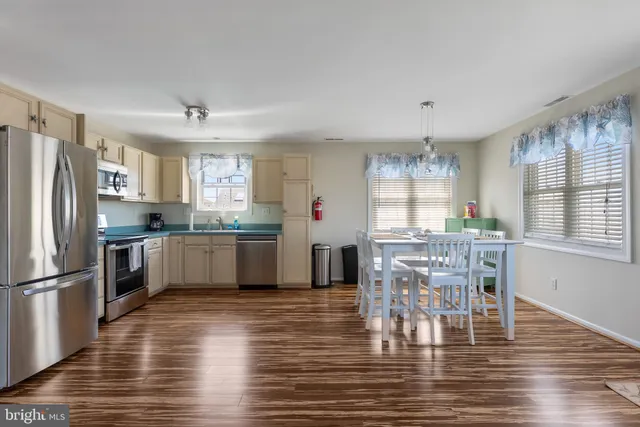 a kitchen with stainless steel appliances granite countertop a refrigerator a stove a sink dishwasher a dining table and chairs with wooden floor