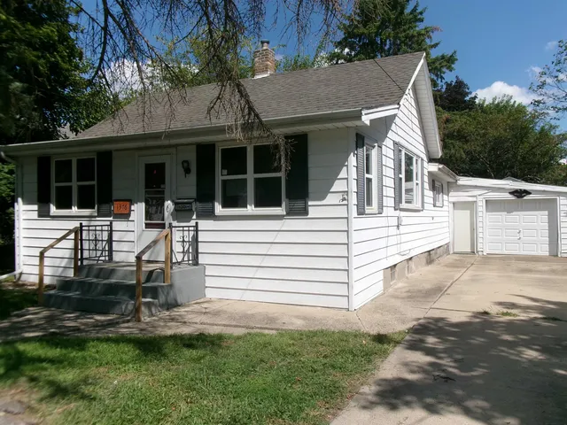 a view of a white house with large windows and a small yard