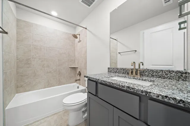 a bathroom with a granite countertop toilet sink and bathtub