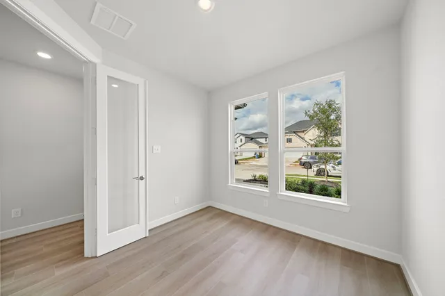 an empty room with wooden floor and windows