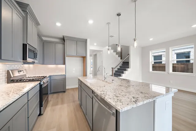 a kitchen with granite countertop kitchen island a stove a sink a oven and wooden floors